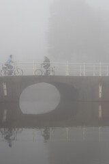 People cycling or waking outdoors during a very foggy, misty day