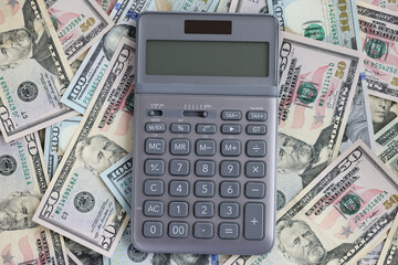 Calculator lying on set of American dollar bills closeup