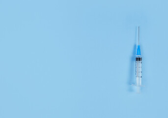 Single use syringe on blue background. Simple flat lay with copy space.