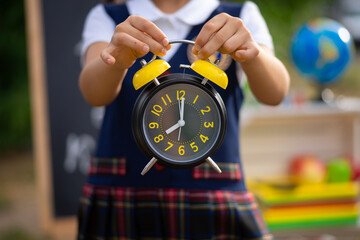 alarm clock in the hands of a schoolgirl. soft focus.