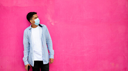 Obraz na płótnie Canvas Young man with surgical mask on pink background: stock photo