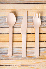 Wooden cutlery stacked on a wooden table. Ecological disposable utensils used at meals.