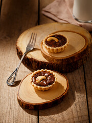 Chocolate tart topping with cashew nuts on wooden table