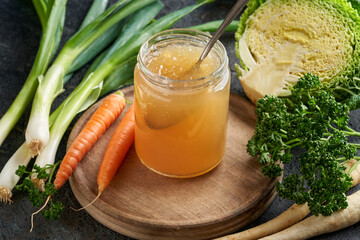 Cooled down congealed beef bone broth in a glass jar with fresh vegetables