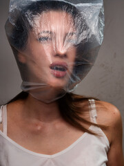 one young woman, chocking on plastic bag. upper body shot.