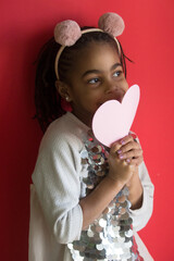 Portrait of a girl with a paper heart on color background	