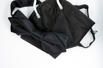 A new concept of style required for adapting to the times of coronavirus. Black bow tie and a black respirator. For everyday life or as an elegant wedding kit for a groom.