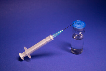 Vaccine bottle phial with no label, medical syringe injection needle. isolated on blue background....