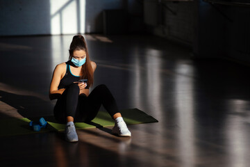 Young sporty woman after practicing yoga, holding smartphone