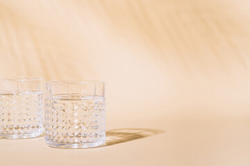 Glass of water on pastel background with hard shadow