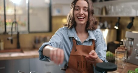 Young cheerful housewife in apron cooking broccoli on the kitchen at home. Happy household chores and healthy eating concept