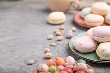 Colored zephyr or marshmallow with cup of coffee and dragees on a gray concrete background. Side view, selective focus, copy space.