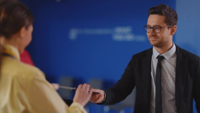 Businessman arriving to the aoirport standing by check-in registration. Polite pretty security agent checking client personal information and visa on computer screen.