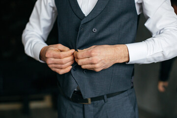 Cheerful young man in a gray suit touches a jacket