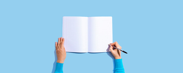 Person writing in a notebook from above