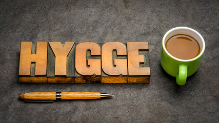 hygge word in vintage letterpress wood type blocks against handmade bark paper with a cup of...