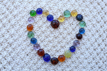 Heart made of small pieces of colored glass, on a white cloth.