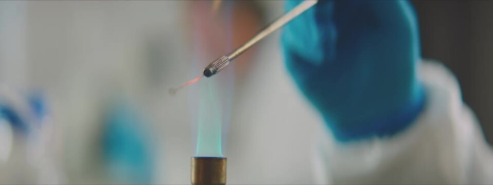 Close-up of human hand holding lap equipment. Disinfecting wire loop in flame. Selective focus. Working in factory laboratory concept.