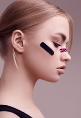 Beautiful blonde girl with glamour plasters on her face