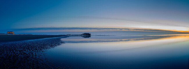 Panorama view of splendid sunset at the Wadden sea of Sankt Peter Ording with stilt houses on the...