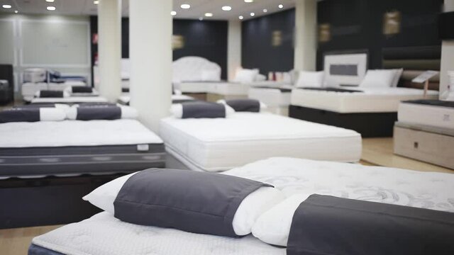 Closeup of new modern orthopaedic mattress on display for sale in large furniture store. High quality FullHD footage