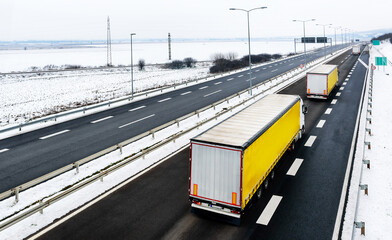 Highway transportation with a convoy of Lorry trucks passing trucks in a snowy winter landscape