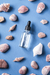 Fototapeta na wymiar Skin care essence oil dropper in glass bottle near to seashells and pebbles