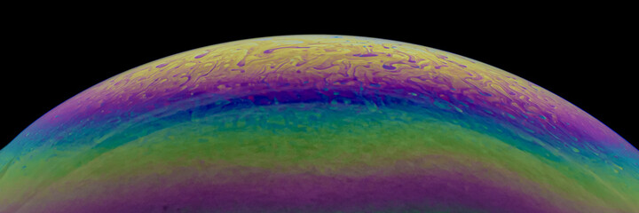 Obraz premium Close up, macro shot of a rainbow, multi colored soap bubble with yellow, purple, pink, blue and green colors on black background. 