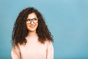 Portrait of a pretty smiling curly young woman in casual posing isolated on a blue background.