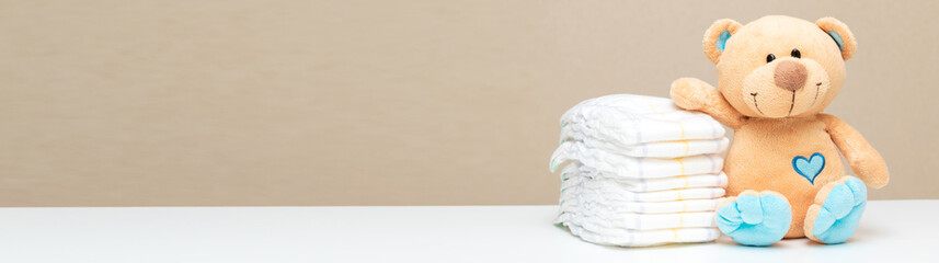 Stack of diapers for baby, toddler with toy teddy bear on table. set for boy girl for baby shower...