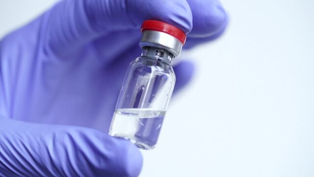 Close-up of a doctor's hands in blue medical gloves hold an ampoule of serum against Coronavirus, COVID-19, influenza, diabetes and other diseases. Vaccination banner concept, copy space. Macro photo
