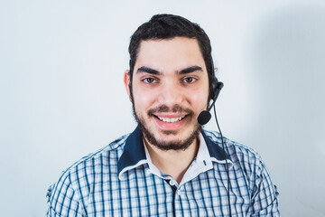 Obraz premium Smiling young office worker wearing a headset and looking at the camera, man with the beard working in the customer service department