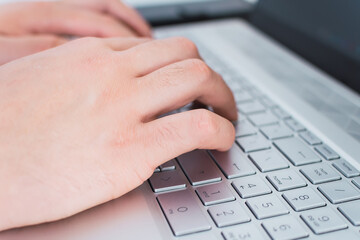 Close up of male hands typing on laptop keyboard.
