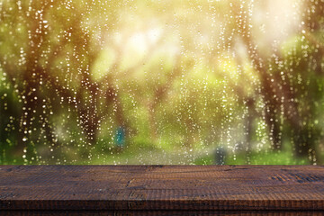 Wood table top on window glass with raindrops after summer rain. Can be used for display or montage your products