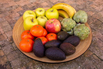 wooden tray with seasoned fruits and vegetables on a ceramic table