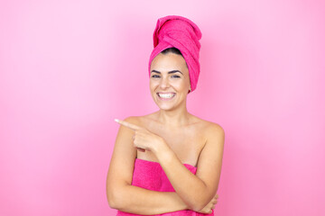 Young beautiful woman wearing shower towel after bath standing over isolated pink background...