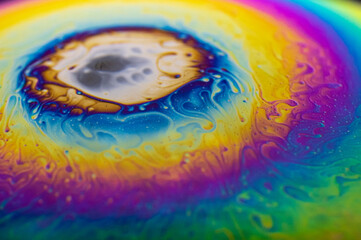 Side of a soap bubble macro, close up detailed shot. Bright, rainbow colors looking like a imitation of space, planet on black background. 