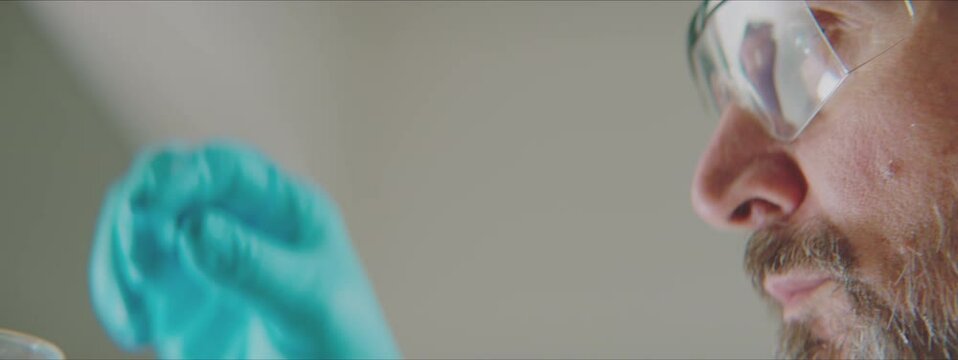 Close-up of lab professional rotating with hydrometer in yellow solution. Working in factory laboratory concept.