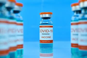 Covid-19 vaccine in bottles on blue table.