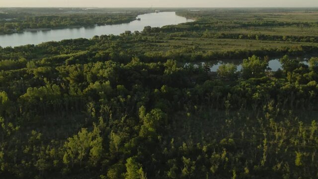 Tilt up revealing Zarate large green fields and forest area and Parana river at golden hour, Entre Rios, Argentina