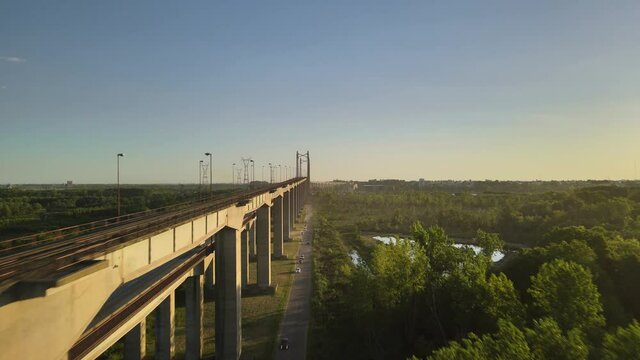 Dolly in flying alongside Zarate Brazo Largo road and railway complex cable-stayed bridge between green fields at golden hour, Entre Rios, Argentina