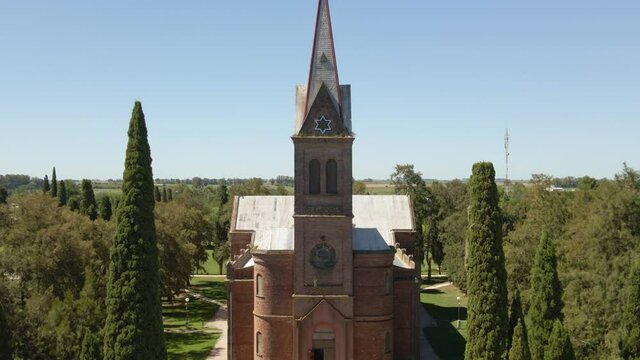 Jib up of beautiful romantic style church and tower surrounded by pine trees in Santa Anita town, Entre Rios, Argentina