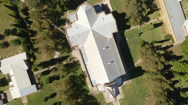 Top down orbital rising of a romantic architectural style church surrounded by trees, Santa Anita, Entre Rios, Argentina