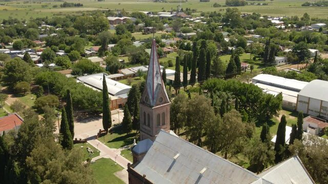 Dolly out of a romantic style church and tower with Santa Anita countryside town in background, Entre Rios, Argentina