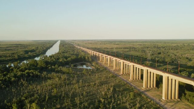 Dolly in of Zarate Brazo Largo road and railway complex cable-stayed bridge between green fields and river at golden hour, Entre Rios, Argentina