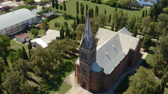 Orbital of beautiful romantic style church surrounded by trees with Santa Anita countryside town in background, Entre Rios, Argentina