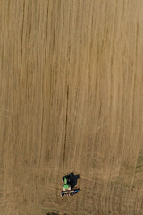 Aerial view large tractor cultivating a dry field. Top down aerial view tractor cultivating ground...
