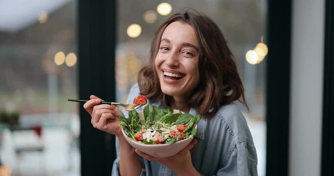 Video Portrait Of A Cheerful Young Woman Eating Healthy Green Salad. Look At Camera And Smiling. Healthy Food And Feeling Well Concept. Dolly Out Shot