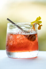 Colorful red fall-inspired cocktail, yellow citrus and flower garnish
