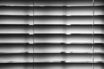 Black and white close up of shadows on a pair of window blinds. 